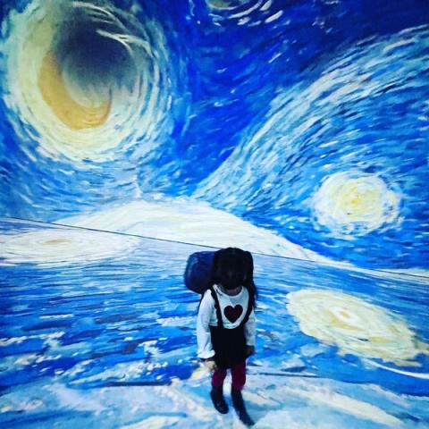 Little girl standing before Van Gogh's Starry Night projection