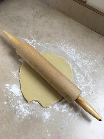 A rolling pin sitting on sugar cookie dough