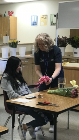 teacher helping student make a ribbon bow