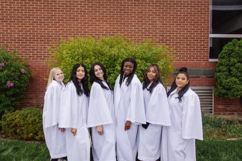 Six girls in white graduation robes