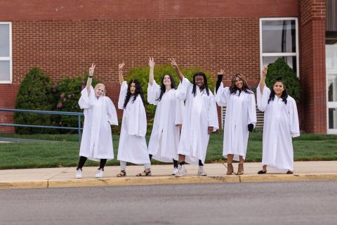 Girls in graduation robes waving