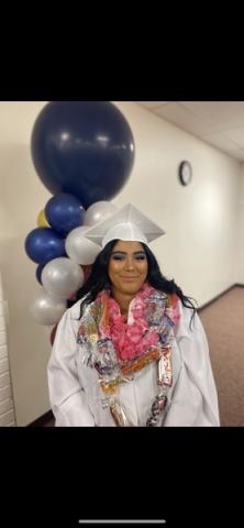 Legacy graduate in graduation robe with balloons in background