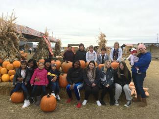 students and teachers posing among pumpkins and hay bales